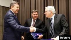 Eduard Stavytskyi, chairman of Ukraine's state geology and mineral resources service (center), watches as Ukrainian President Viktor Yanukovych (left) shakes hands with Peter Voser, CEO of Royal Dutch Shell in Davos, on January 24.