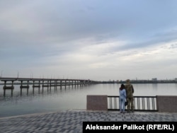 A soldier and a woman stand at the banks of the Dnieper River.