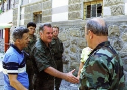 Bosnian Serb Commander Ratko Mladic (left) shakes hands with one of his soldiers inside Srebrenica after seizing the enclave on July 11.