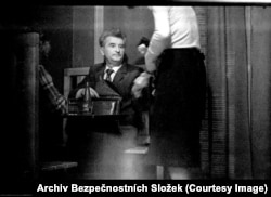 A man pays for drinks after meeting with a friend in a gloomy Prague wine bar.