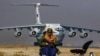 A Taliban fighters sits guard in the backdrop of a Russian plane transporting aid relief donated by Russia for the Afghan people, at Kabul Airport on November 18. 