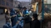 A man distributes bread to burqa-wearing women outside a bakery in Kabul in December.