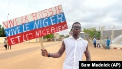 A supporter of Niger's ruling junta holds a placard in the colors of the Russian flag reading "Long Live Russia, Long Live Niger and Nigeriens" at the start of a protest called to fight for the country's freedom and push back against foreign interference in Niamey, Niger, on August 3, 2023.