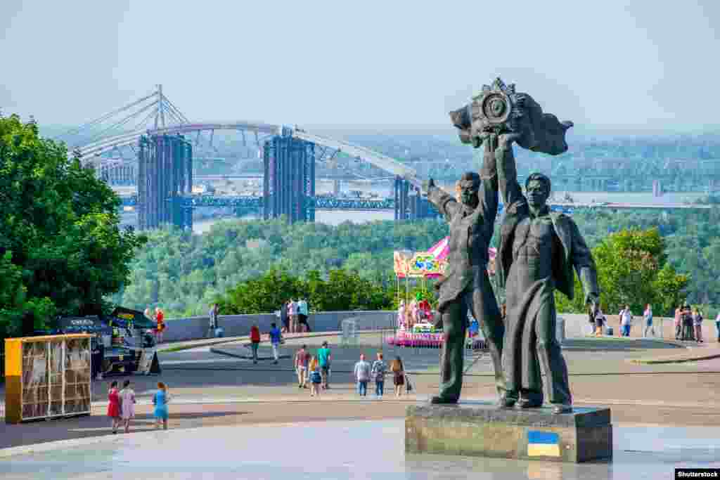 A June 2018 photo of the two main figures of a Soviet-era landmark originally called the Monument to Commemorate the Reunification of Ukraine with Russia in central Kyiv. The statues, representing a Russian and Ukrainian worker uniting under a Soviet state emblem,&nbsp;were cut down in April 2022. One month later, the monument complex, which is marked by a large titanium arch, was renamed the Arch of Freedom of the Ukrainian People. &nbsp;