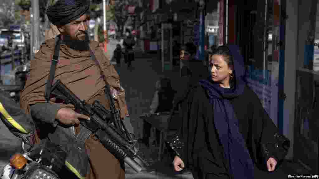 A Taliban fighter and an Afghan woman eye one another in Kabul in December 2022. Since their return to power in August 2021, the hard-line Islamists have waged a brutal crackdown on dissent and reintroduced their extreme and tribal interpretation of Islamic Shari&rsquo;a law.