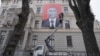 A man installs an anti-Putin poster on a building in the Latvian capital, Riga. (file photo)