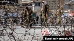 Taliban fighters stand guard at the explosion site near the Foreign Ministry in Kabul on March 27.