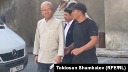 Adakhan Madumarov (left) is taken away from the Ministry of Internal Affairs for a court session in Bishkek on September 2.