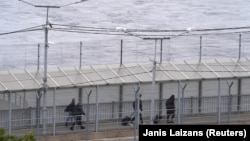 People walk on the bridge over the Narva River at the border crossing point with Russia in Narva, Estonia.