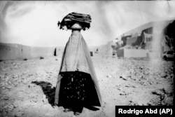 A woman in a burqa walks home carrying bread for her family and neighbors in Bamiyan on June 18.