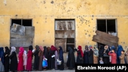 Afghan women wait to receive food rations distributed by a humanitarian aid group in Kabul on May 28.