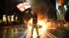 A man waves a Georgian national flag in front of a burning barricade during protests in Tbilisi this week against a controversial 'foreign agent' bill. 