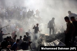 Palestinians in the rubble of destroyed buildings following Israeli air strikes on the town of Khan Yunis in the Gaza Strip on October 26, 2023.