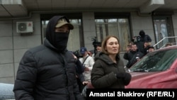 24.kg Director-General Asel Otorbaeva (right) is escorted by Kyrgyz security officers from the news outlet's offices in Bishkek on January 15. 