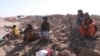 People affected by the recent earthquakes sit on the debris of demolished houses in the Zendajan district of Afghanistan's western Herat Province on October 16.