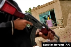 A Taliban fighter stands guard at the site of an explosion in front of a school, in Kabul on April 19.