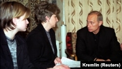 Russian President Vladimir Putin (right) talks with Irina Lyachin, the wife of the commander of the Kursk submarine, and her daughter in their flat in the naval town of Vidyayevo on August 22, 2000. 