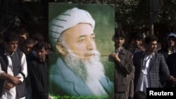 Supporters of Burhanuddin Rabbani hold a portrait of him as they stand outside his house in tribute after he was assassinated in September in Kabul.