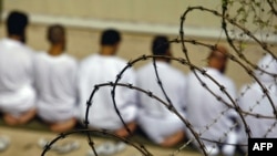 In this picture from 2009, a group of detainees at the Guantanamo Bay U.S. detention center kneels during morning prayers.