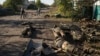 Local residents pass by the dead bodies of Russian soldiers on a street in the recaptured city of Lyman in the Luhansk area of Ukraine in October 2022.