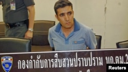 Suspect Mohammad Hazaei sits behind Thai immigration police sign after he was arrested at Suvarnabhumi Airport in Bangkok on February 14.