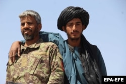 An Afghan Taiban militant poses for a picture with an army soldier during the brief cessation of hostilities.