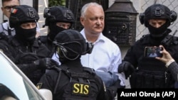 Members of Moldova's Information and Security Service (SIS) escort former Moldovan President Igor Dodon (center) to a van after he was detained at his house in Chisinau on May 24.