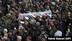 Iranian policemen carry a the coffin of colleague a colleague who was one of three officers killed last month when a bus rammed into them in February. 