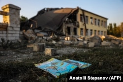 A schoolbook lies in front of a destroyed school building following a missile strike in Druzhkivka, Donetsk region, on August 30.