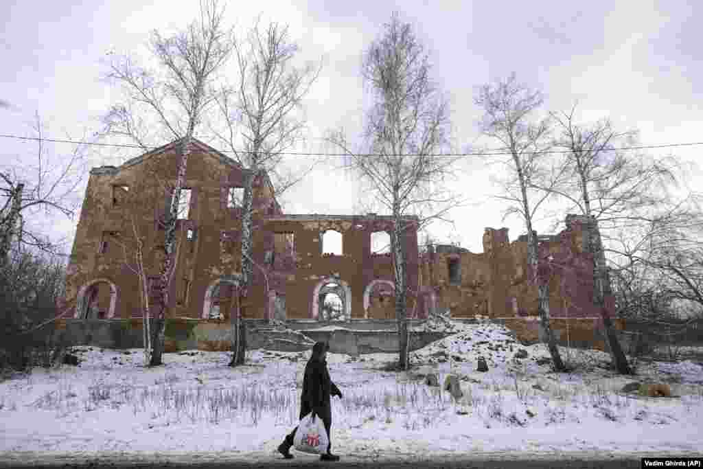 A local woman walks past a building destroyed during fighting between the Ukrainian military and the separatists in 2014. The photo was taken on the outskirts of Slovyansk in the Donetsk region on January 30.