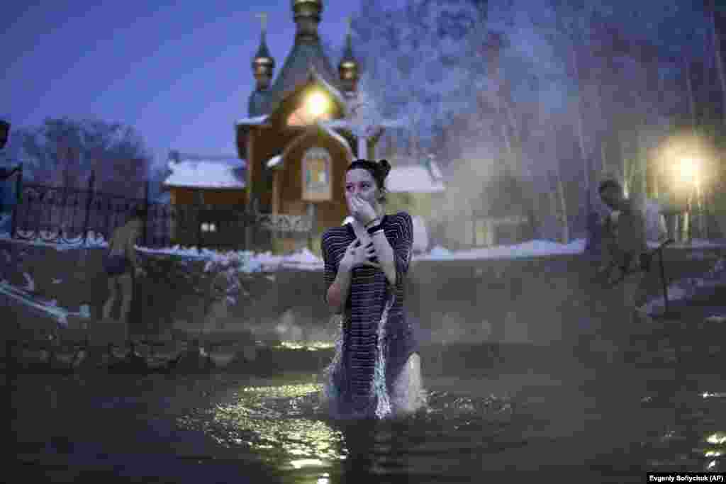 A woman reacts to the freezing water near the monastery in the early morning hours. The Epiphany is frequently marked by a dip in water to symbolize Christ&#39;s baptism in the River Jordan. &nbsp;