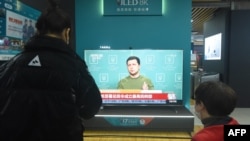 People watch a TV screen showing news about Russia's invasion of Ukraine at a shopping mall in Hangzhou, in China's eastern Zhejiang Province, on February 25, 2022.