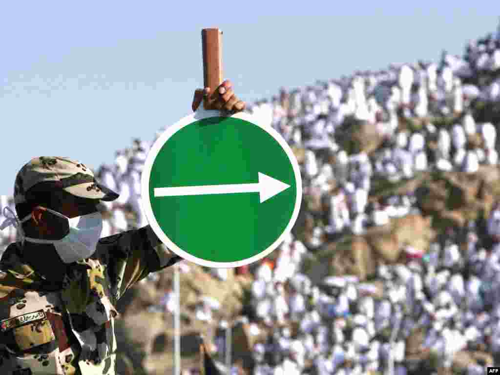 Near the culmination of the hajj, pilgrims spend a day in supplication on the Plain of Arafat. Here, a Saudi police officer wearing a surgical mask during the flu-affected hajj of 2009 helps direct foot traffic. In 2013, deaths blamed on the Middle East Respiratory Syndrome virus were expected to reduce the number of participants.