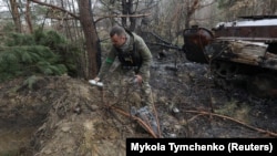 A military sapper picks up unexploded parts of a cluster bomb in the Kyiv region, Ukraine, on April 10, 2022.