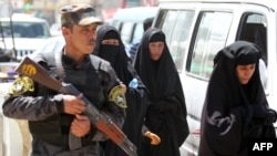 A police officer stands guard as Shi'ite Muslim women walk to the Kadhimiya area of north Baghdad.