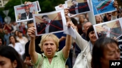 Demonstrators hold aloft pictures of Delyan Peevski at a rally in Sofia. (file photo)