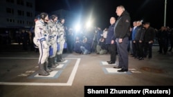 Roskosmos chief Dmitry Rogozin (right) greets International Space Station crew members shortly before their departure from the Baikonur Cosmodrome in Kazakhstan in March 2019.