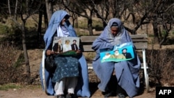 Two women hold posters of presidential candidate and former Islamist warlord Abdul Rasul Sayyaf in the western Herat Province. Women are expected to play a larger role in this election.