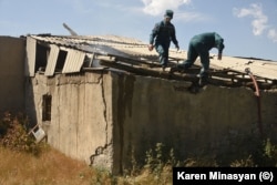 Firefighters descend from the roof of a building still smouldering from reported overnight shelling in Sotk on September 14.