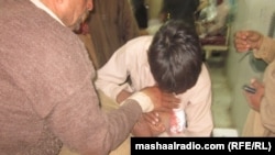 A man holds an injured relative after an explosion in Peshawar during a funeral ceremony killed at least 15.