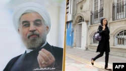 A woman walks past a campaign poster of Hassan Rohani in Tehran ahead of the June election.