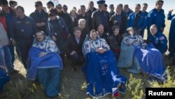 Canadian Chris Hadfield, Russian Roman Romanenko, and American Tom Marshburn rest after leaving the Russian Soyuz space capsule following its landing in Kazakhstan on May 15.