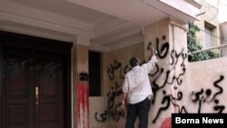 A government supporter spraypaints on the wall of the building where Mehdi Karubi lives in March. His building has been targeted for vandalism before.