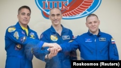 Crew members Chris Cassidy of NASA (left to right) and Anatoly Ivanishin and Ivan Vagner of Roskosmos pose for a picture behind a glass wall during a final news conference ahead of their mission to the International Space Station in Baikonur on April 8.