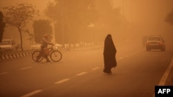 People cross a street as a heavy sandstorm hits the Iranian city of Ahvaz.