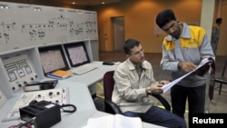 An Iranian operator (right) and a Russian operator discuss a document as they monitor the nuclear power plant unit in Bushehr.