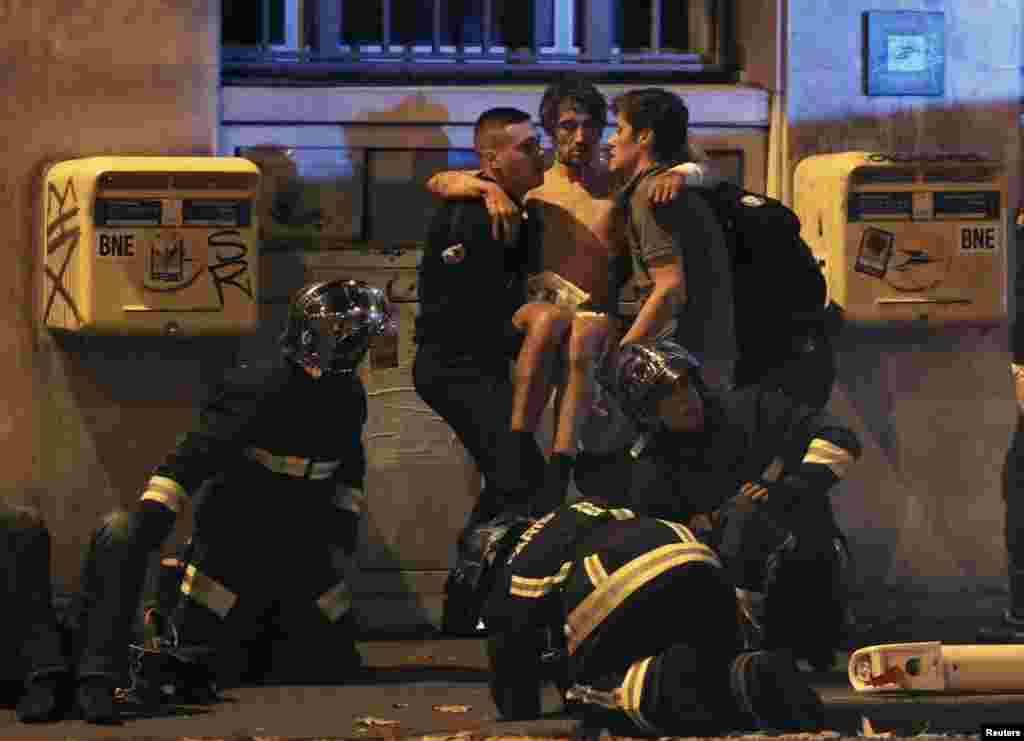 French fire brigade members aid an injured man near the Bataclan concert hall following the fatal shootings in Paris, France.