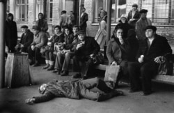 A man dozes on the pavement at a Novokuznetsk bus stop.