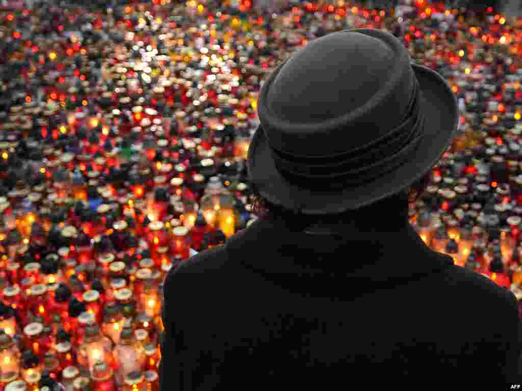 A woman stands in front of a sea of candles laid out outside the presidential palace in Warsaw.