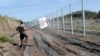 A Hungarian soldier carries a border sign to install at a fence near the town of Morahalom, at the Serbian border, on August 24.